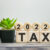 2022 tax - financial concept. Wooden cubes and flower in a pot.